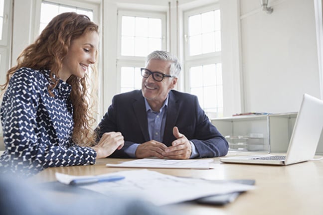 Man and woman at desk discussing plans