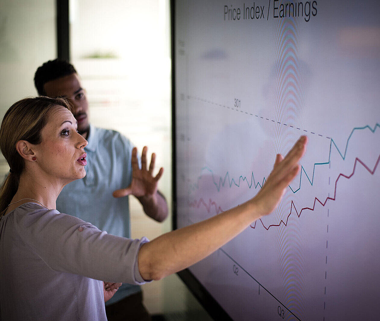 Two people looking at a chart on a large screen.