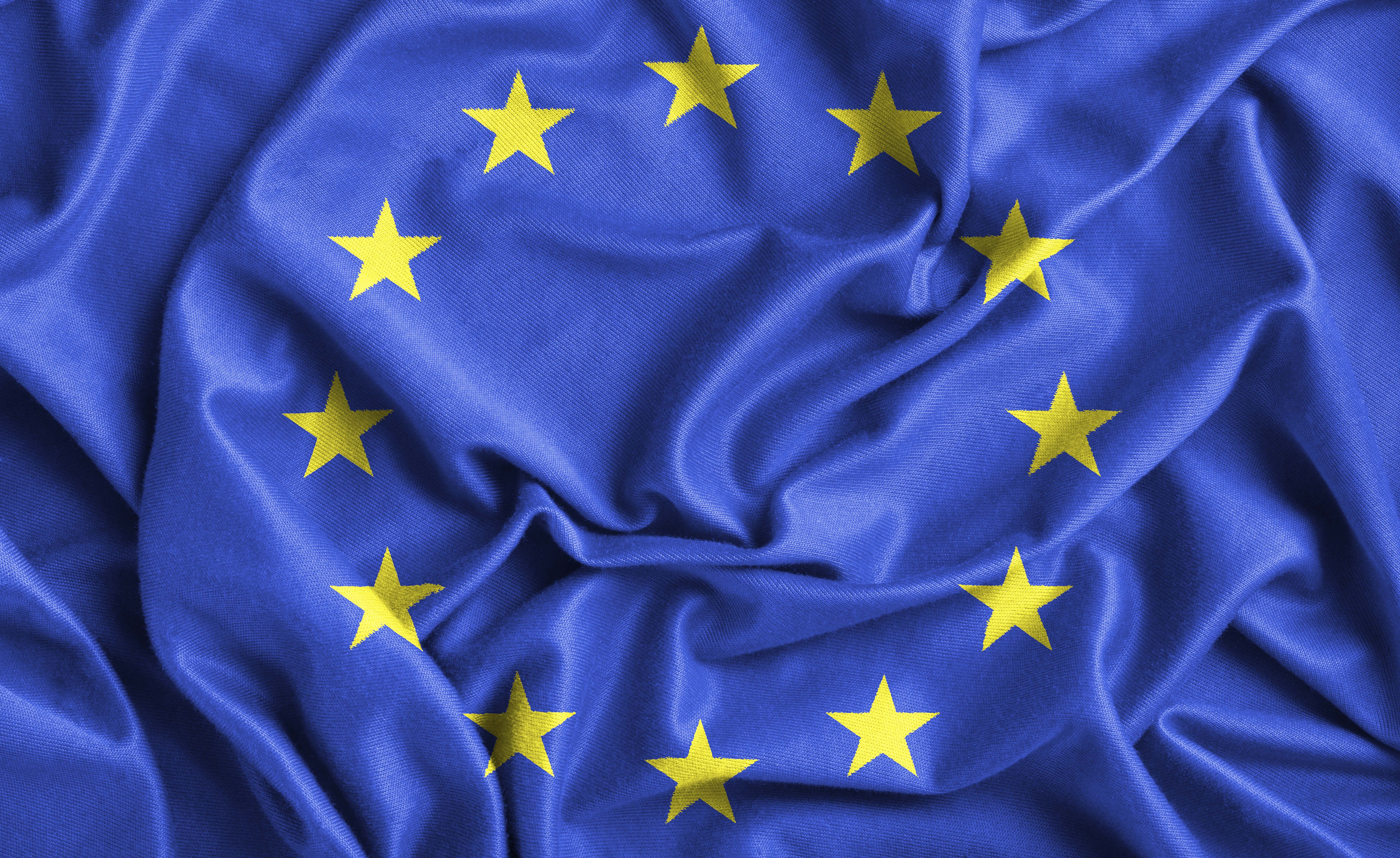 A close up of the European Union blue flag with 12 yellow stars arrranged in a circle