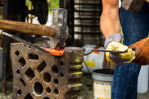 Tools used by a farrier, including a large hammer, for moulding a metal.