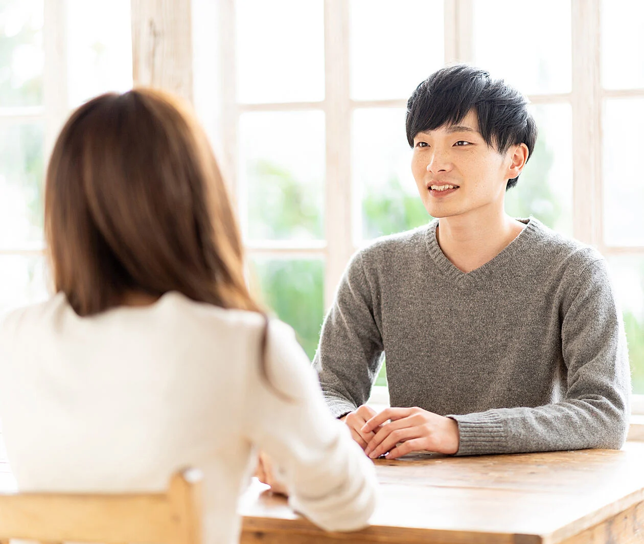 a man practicing speaking at a wooden table facing another person