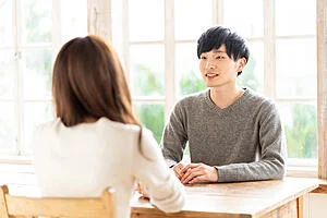 a man practicing speaking at a wooden table facing another person