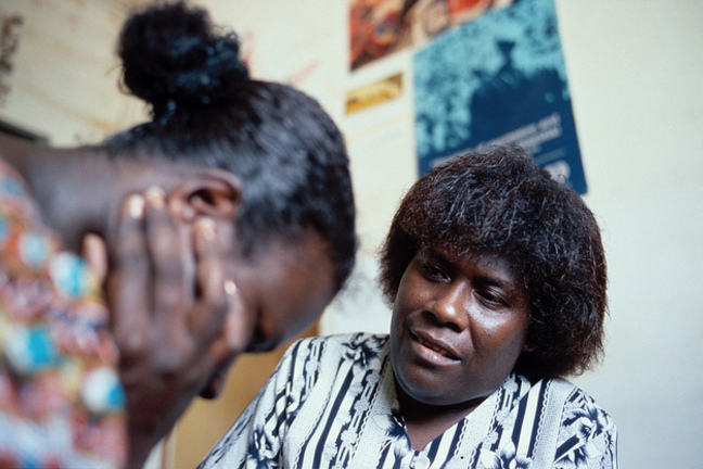 A distraught woman with her head in her hands is being counselled by another woman.