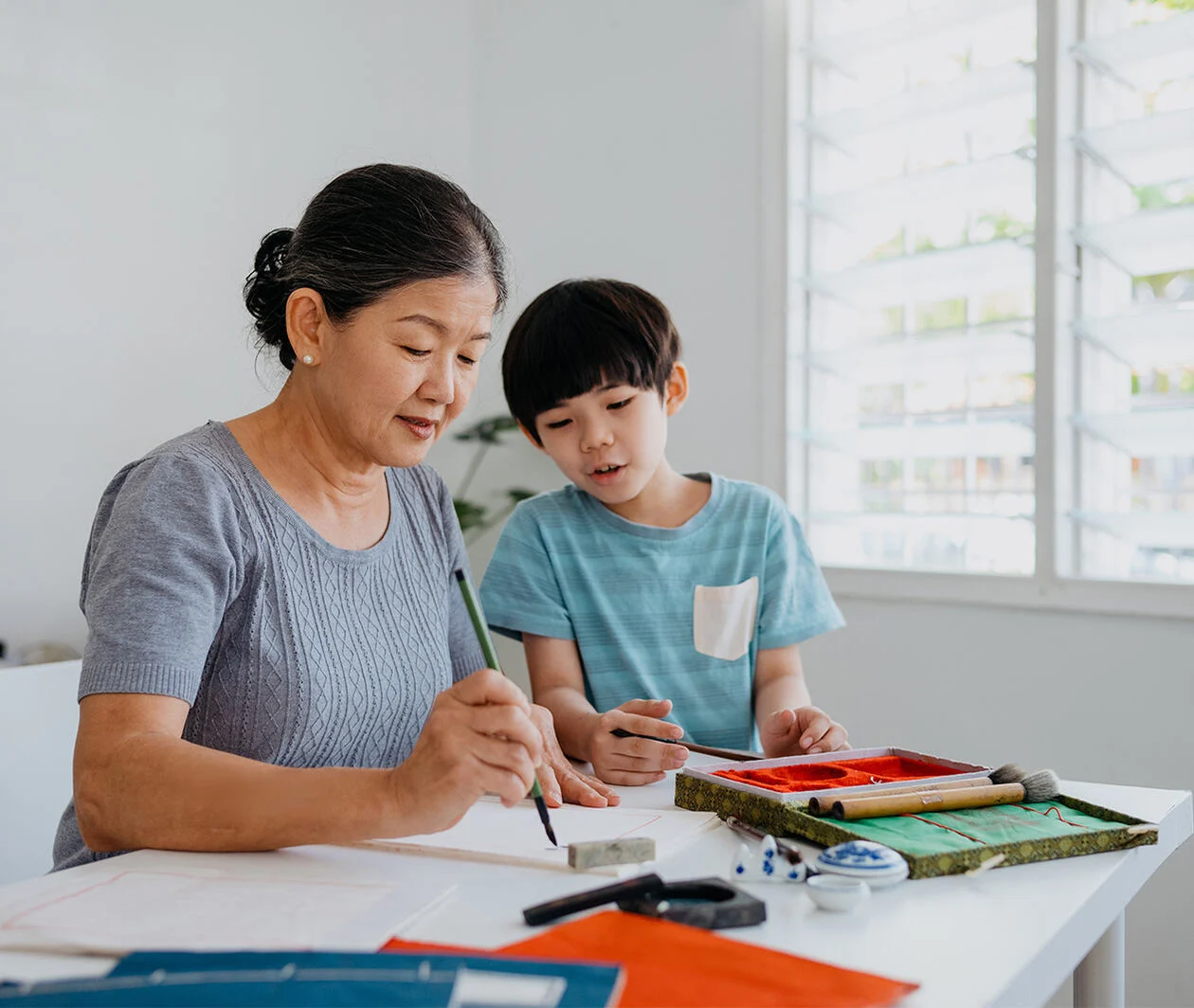 Senior asian woman teaching her grandson Chinese calligraphy 