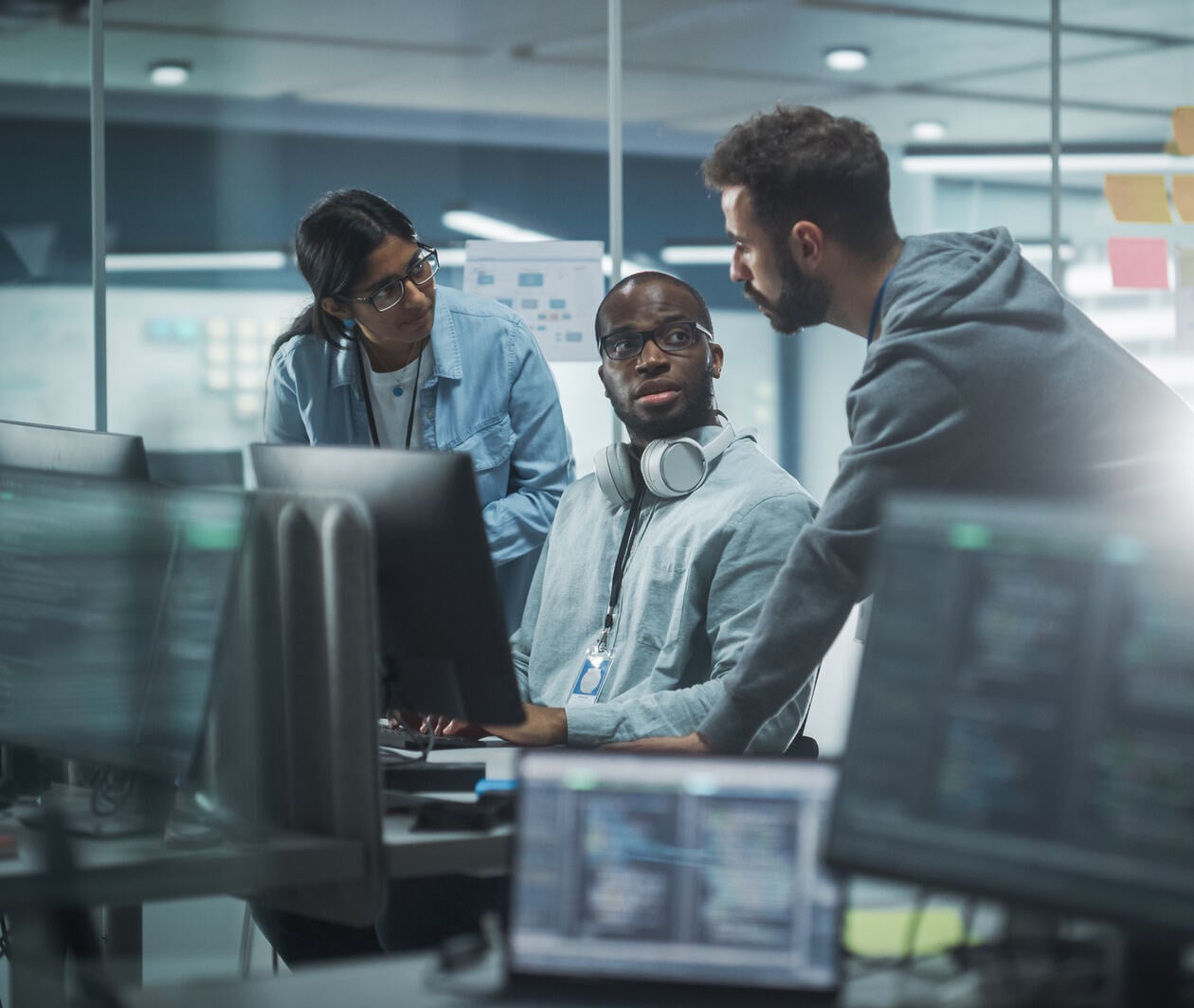 three colleagues looking at one computer screen and discussing what they see