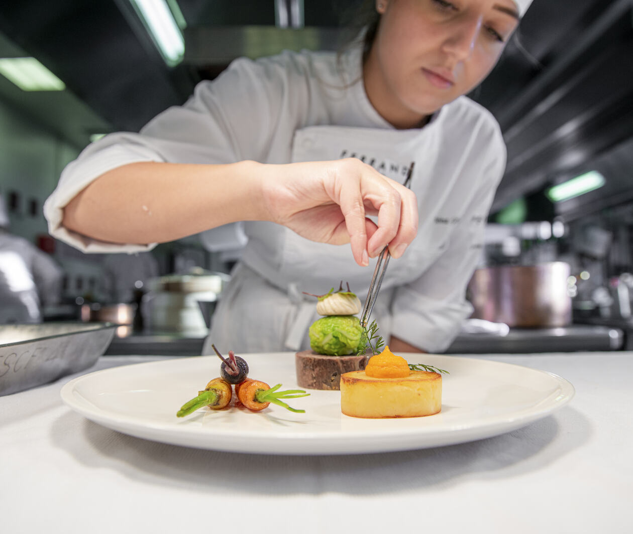 Close-up of a chef plating up plate of French cuisine in a restaurant kitchen.