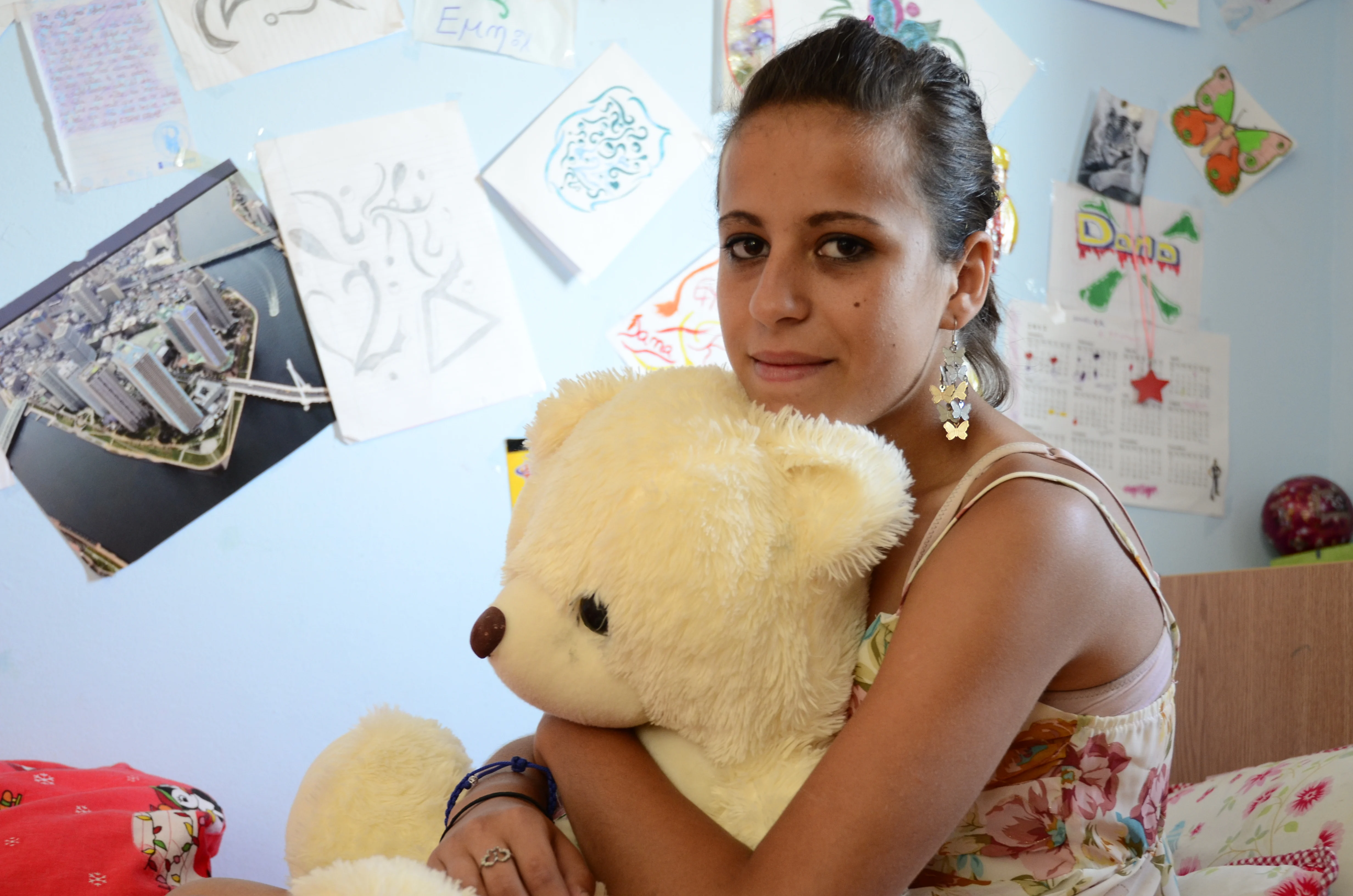 Young woman with sitting on bed clutching a soft toy