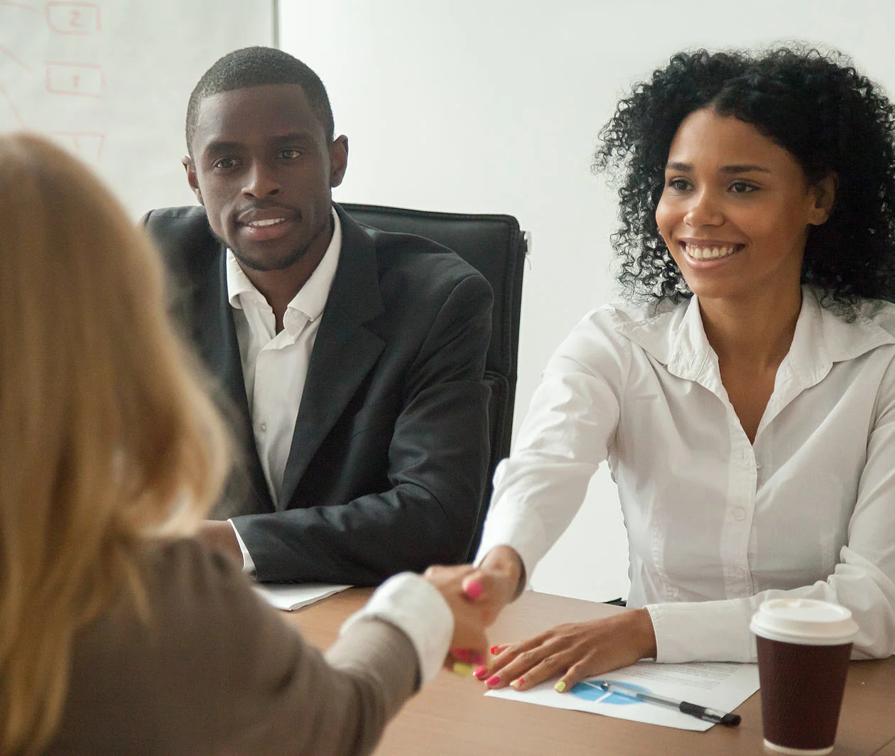 a woman and man shaking hands signing a contract