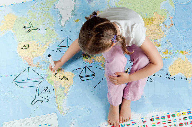 Image of young girl sitting on a map and drawing