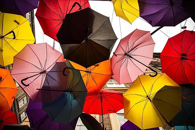 Multiple multicoloureded umbrellas, opened and clustered together.