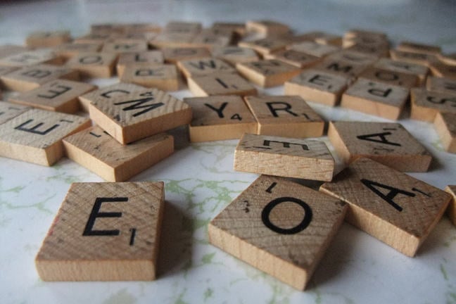 Wooden letter tiles tumbled in a heap.