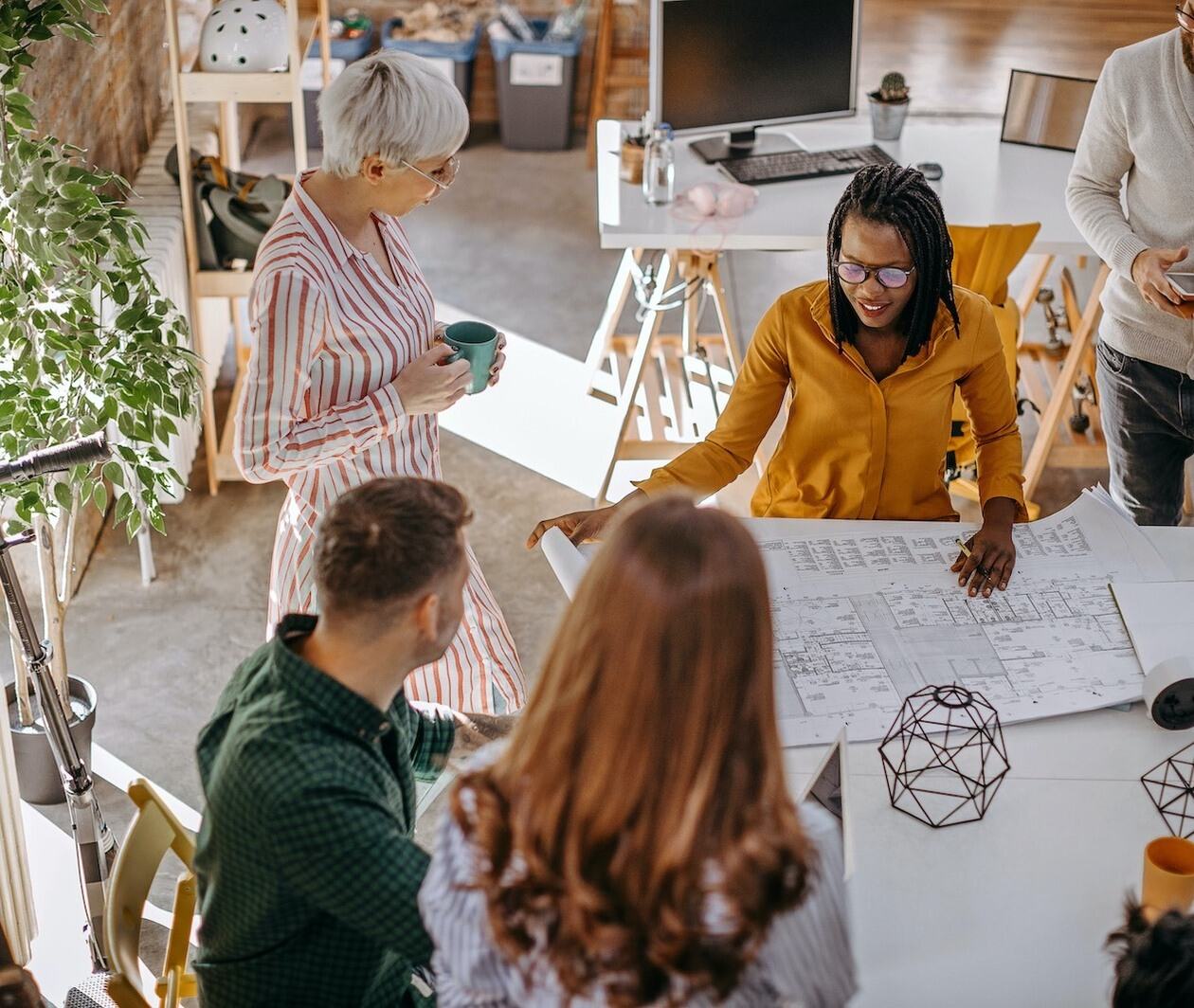 Team of researchers collaborating around a plan on a table