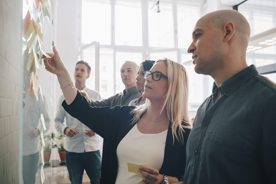 Finding solutions to problems involves several different processes. A group of office employees standing around a whiteboard.