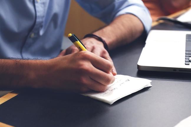 Man writing on a sheet of paper.
