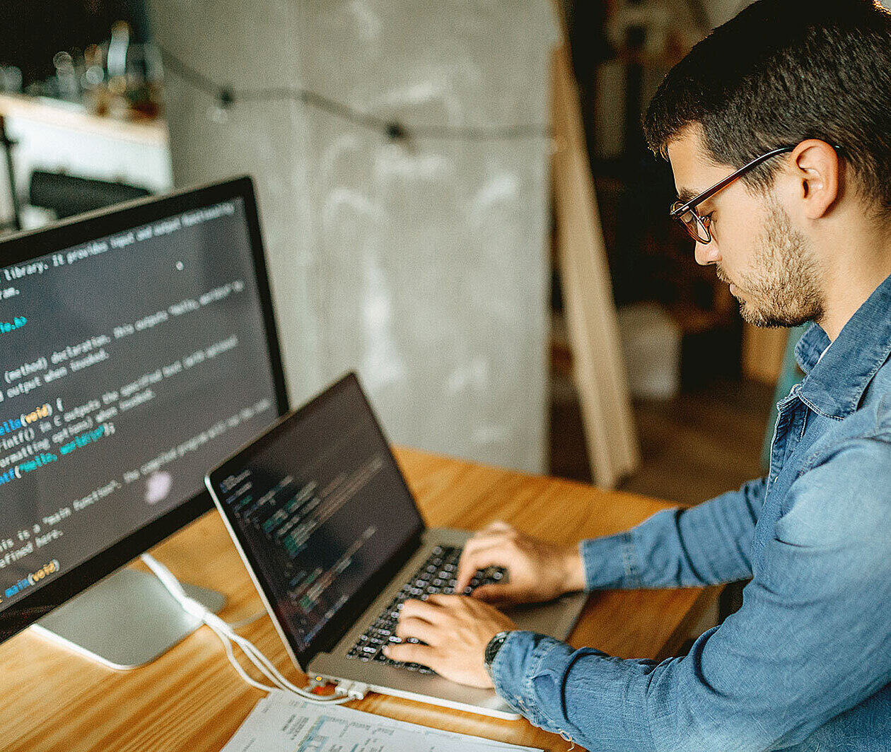 Man working on two screens of code.