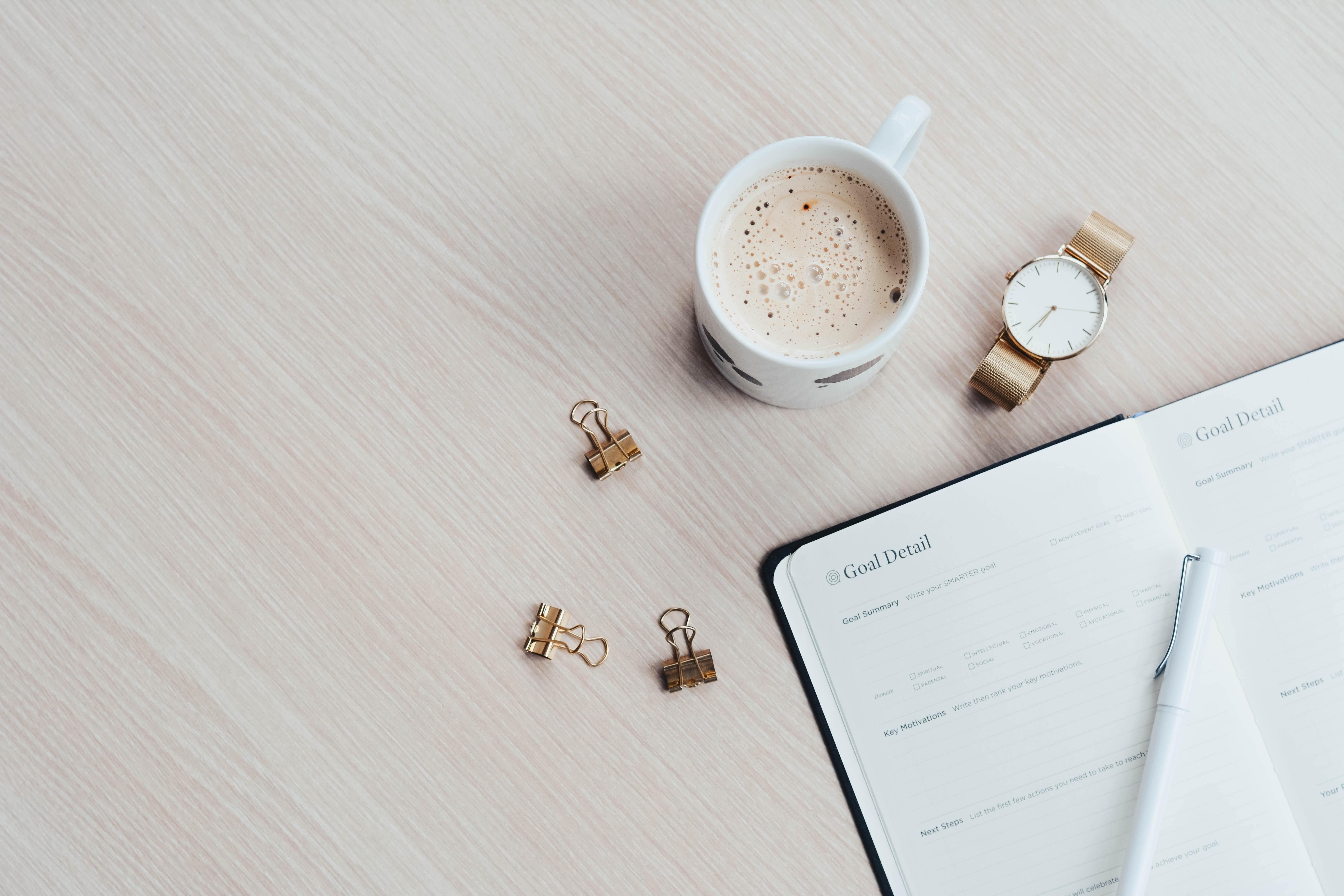 A desk with coffee and a notebook