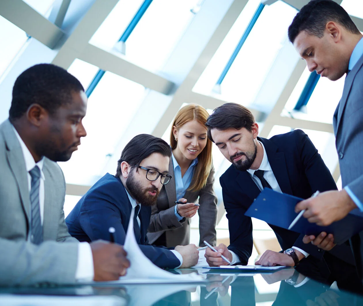 Image of mutiracial business man and women gathered together discussing a document