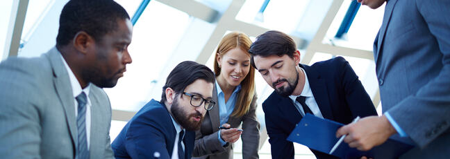 Image of mutiracial business man and women gathered together discussing a document