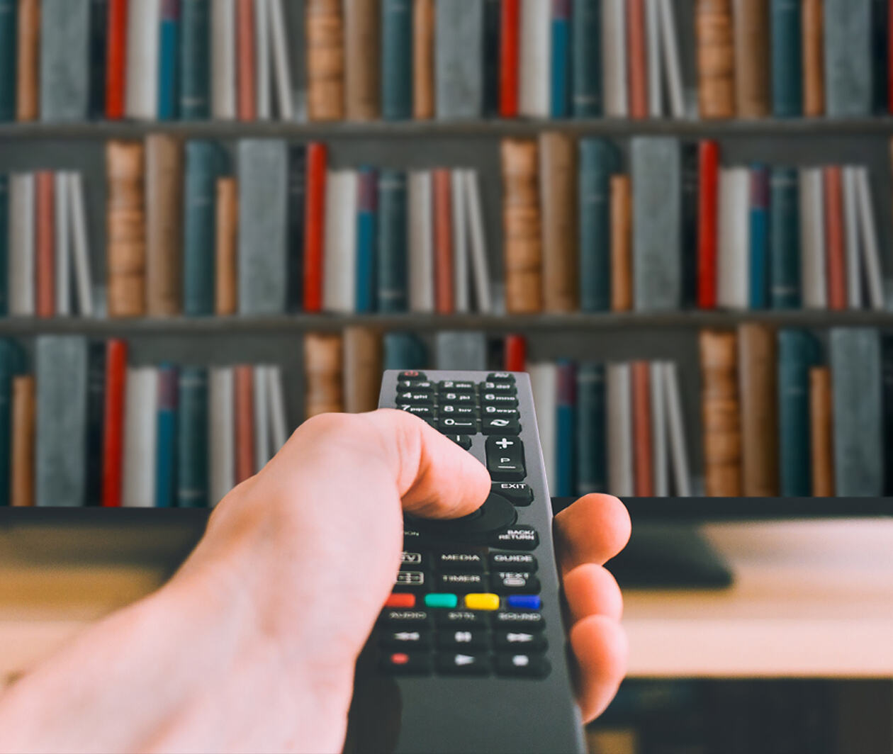 TV remote pointing at TV showing a bookcase full of books