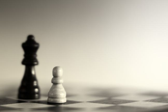 A chess board with 2 chess pieces - a black bishop and a white pawn