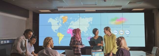 A group of multiethnic people in a roundtable discussion in front of a world map background
