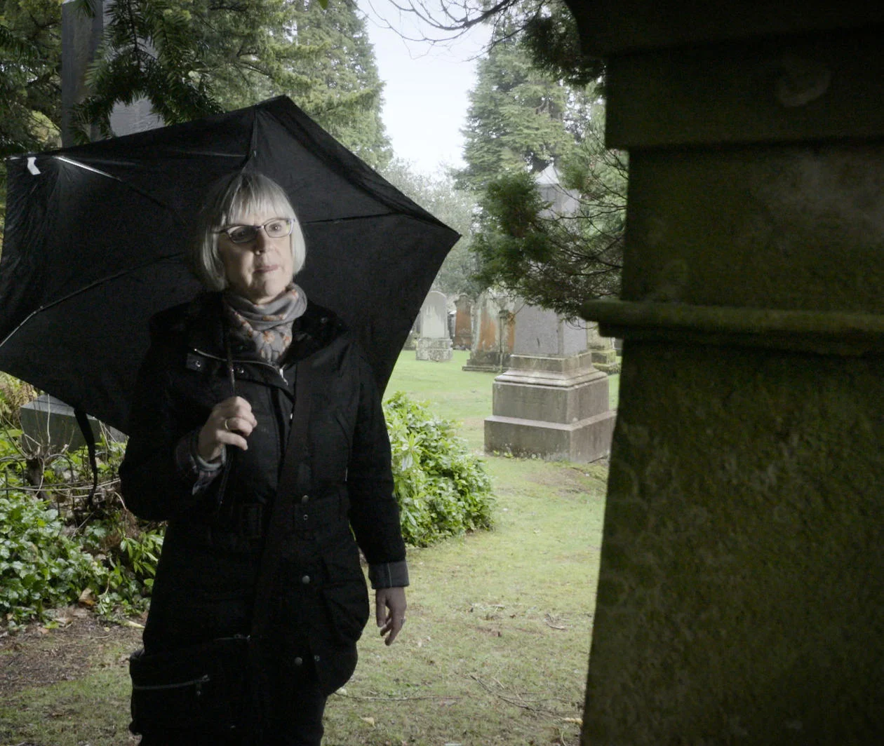 Genealogy: a lady looks at a tombstone in a graveyard while researching her family tree