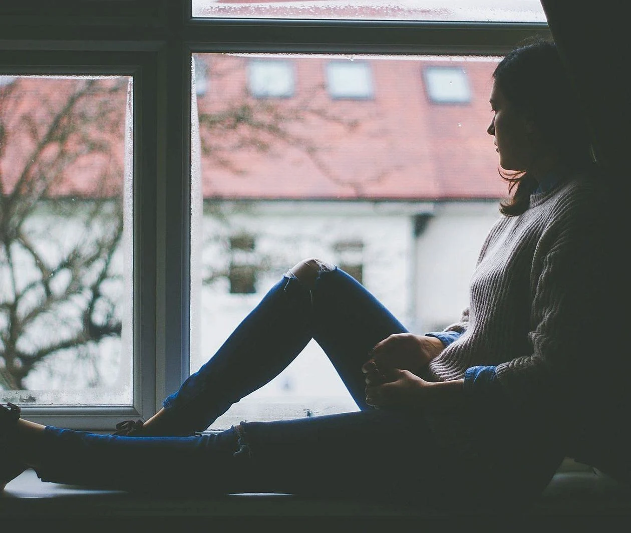 Lady sitting by a window looking out. Image from https://www.pikist.com 