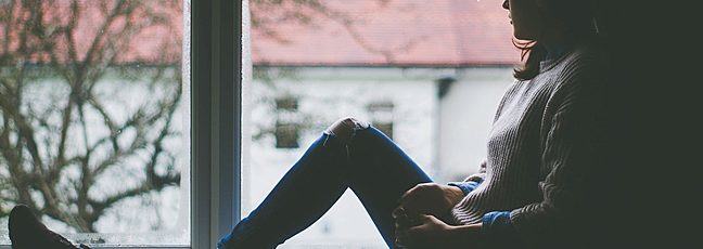 Lady sitting by a window looking out. Image from https://www.pikist.com 