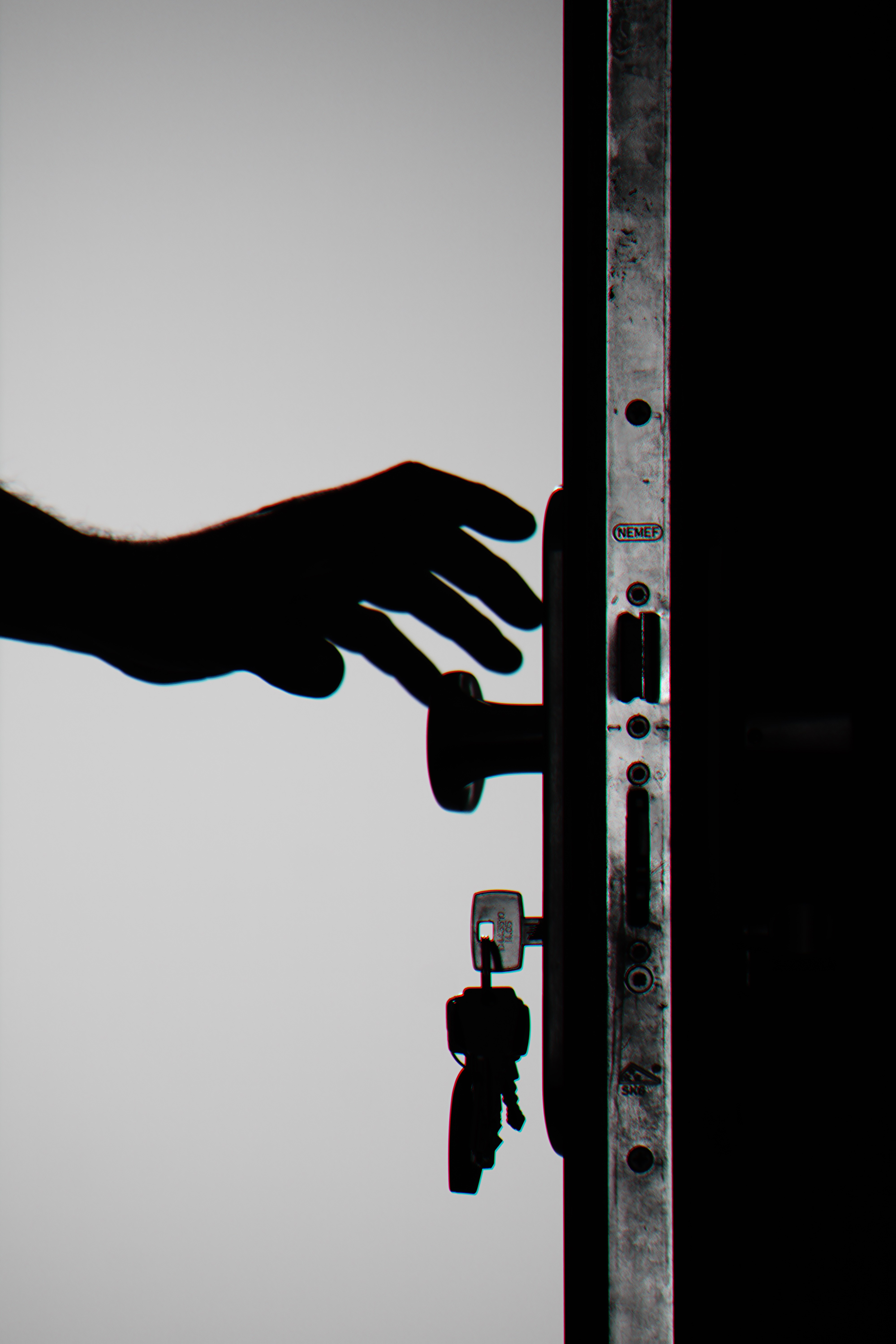 Silhouette of a door in black and white, with a hand reaching out to grasp the handle.