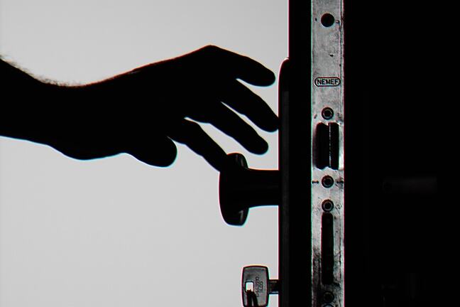 Silhouette of a door in black and white, with a hand reaching out to grasp the handle.