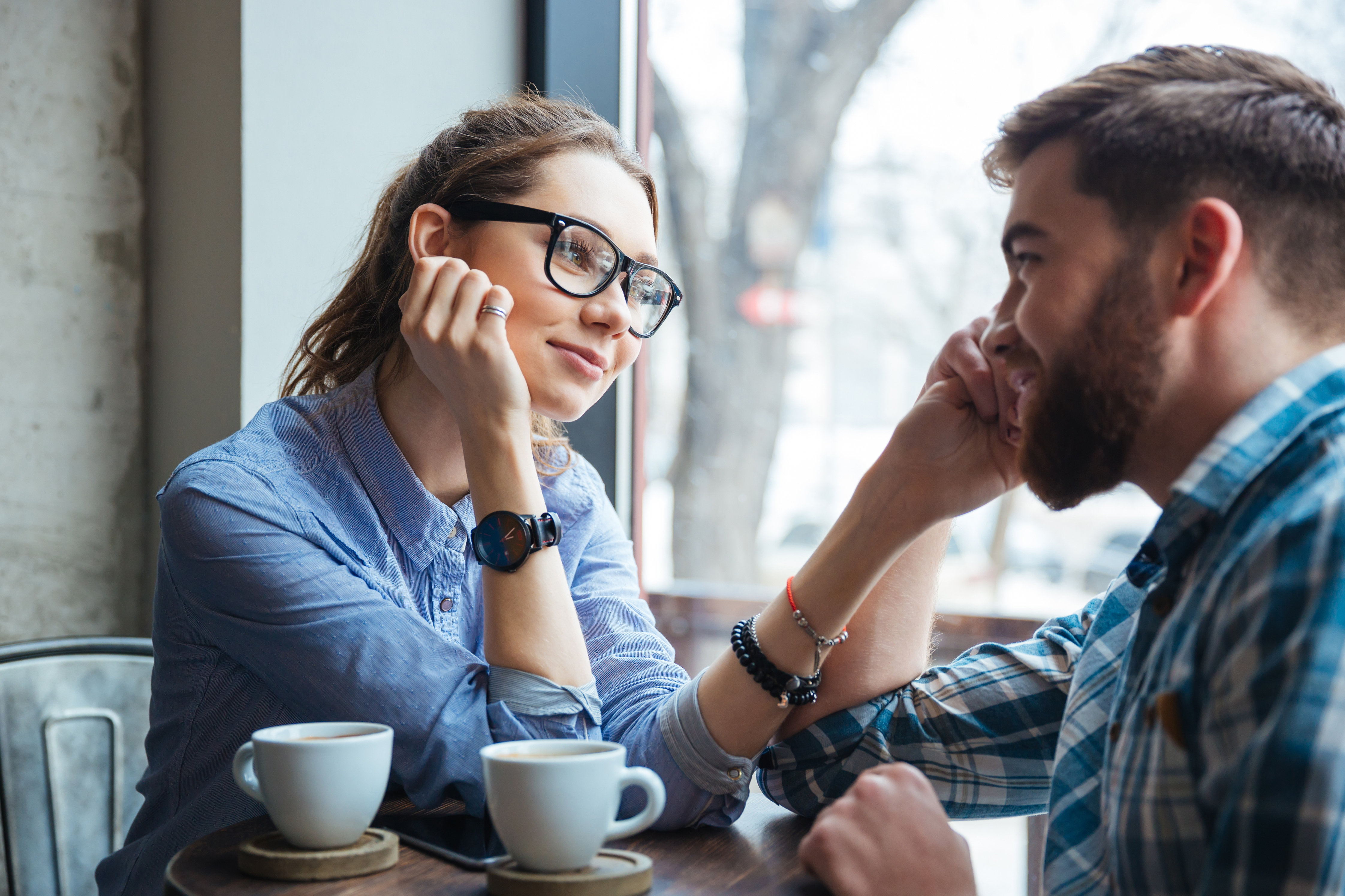 A woman with glasses looking at her partner in a coffee shop.