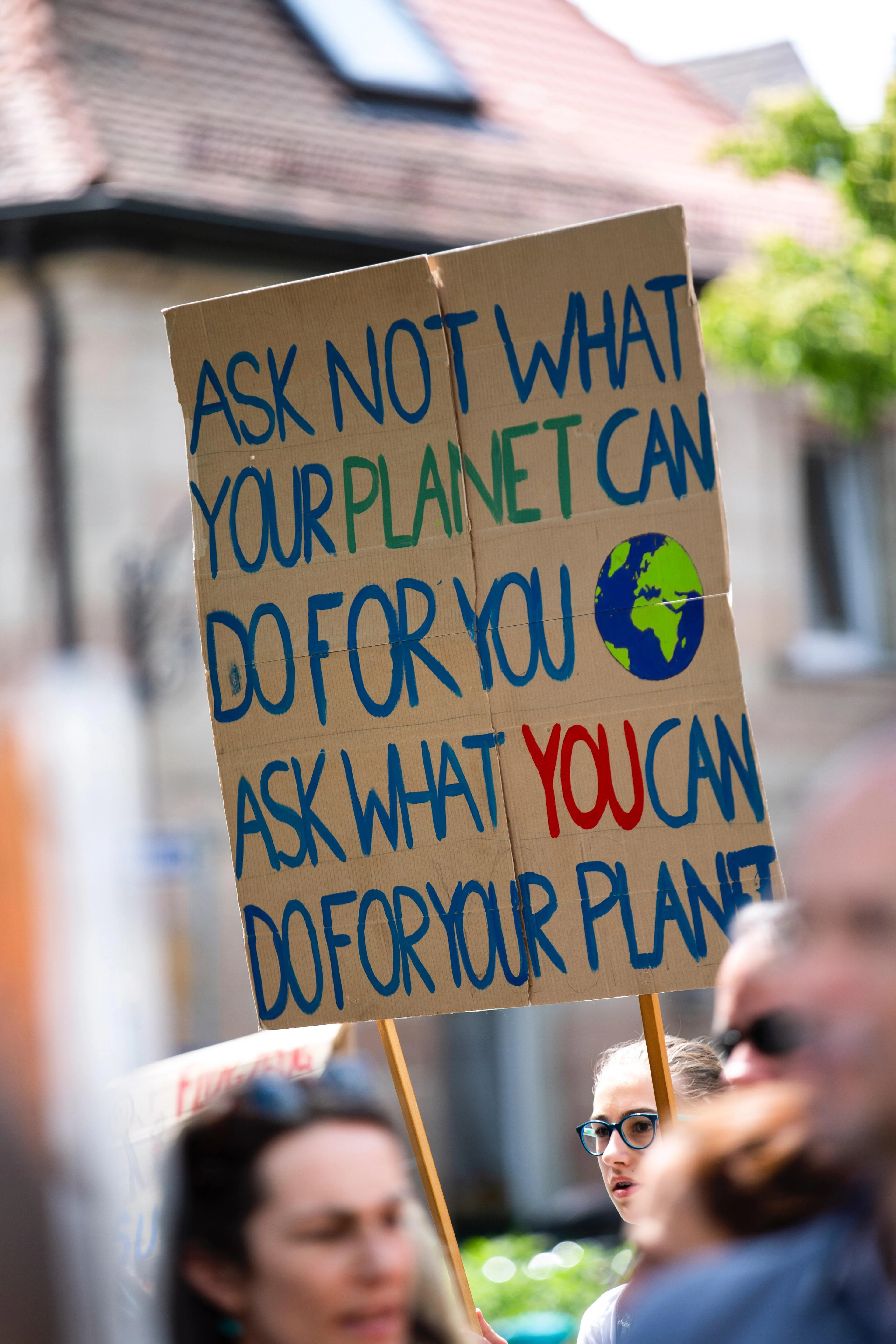 A Fridays for the Future protest cardboard sign reading - Ask not what your planet can do for you. Ask what you can do for your planet.