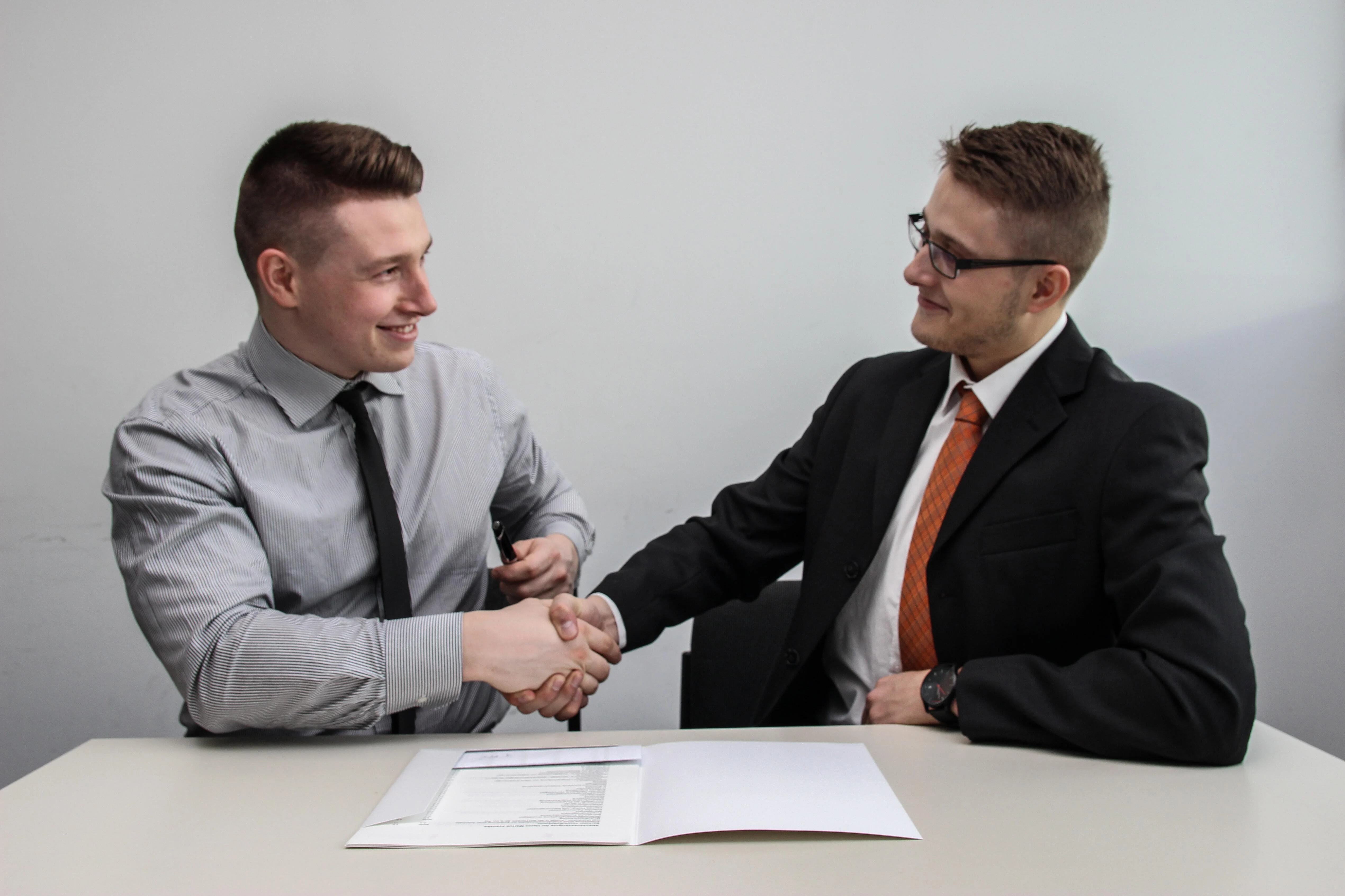 Two men shaking hands with a report infront of them