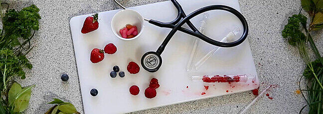 Chopping board with stethoscope and berries in a test tube. 