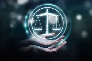 a picture of open hands cradling a graphic of the glowing scales of justice