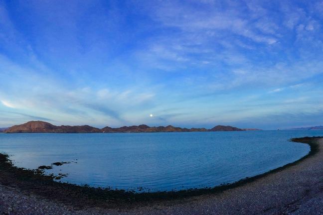 A panoramic view of moonrise over a bay.