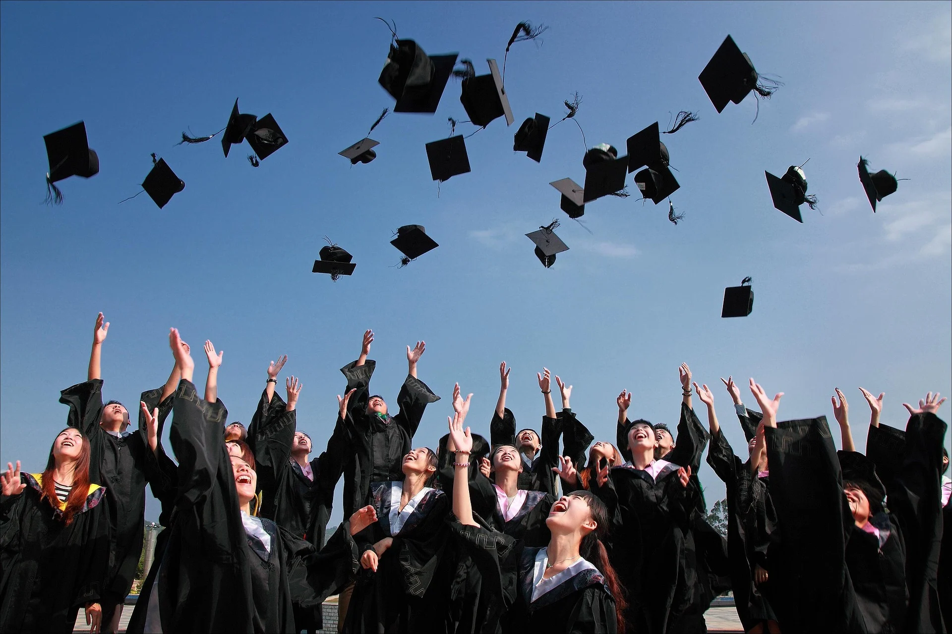 photograph of graduating students in graduation robes throwing their graduation scrolls in the air