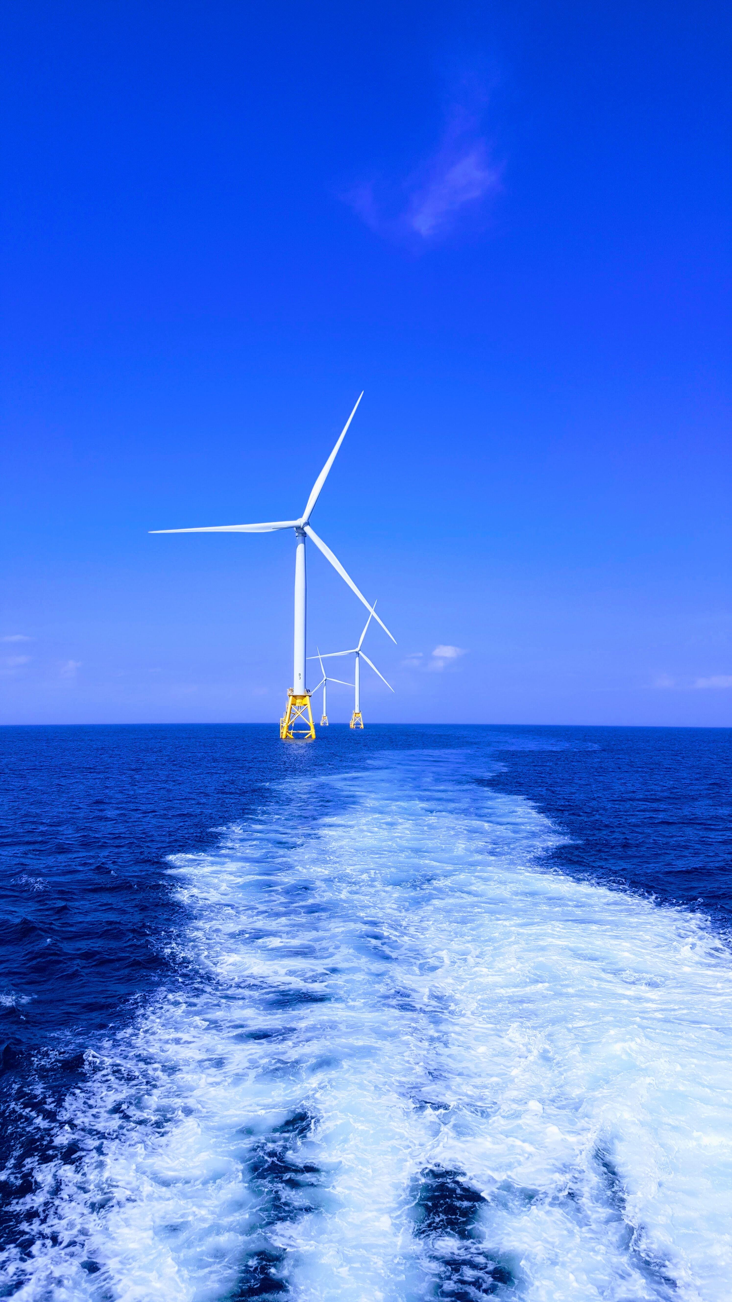 Three wind turbines out in the open sea.