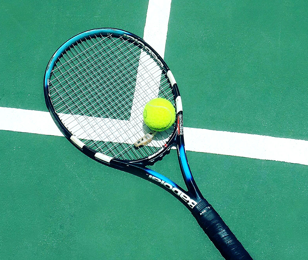 A tennis racket and boll laying on a painted court