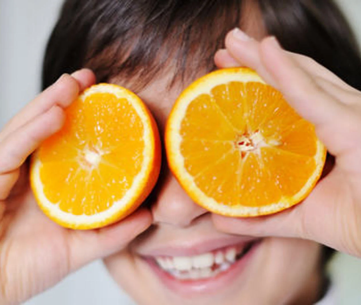 boy with orange slices held to his eyes