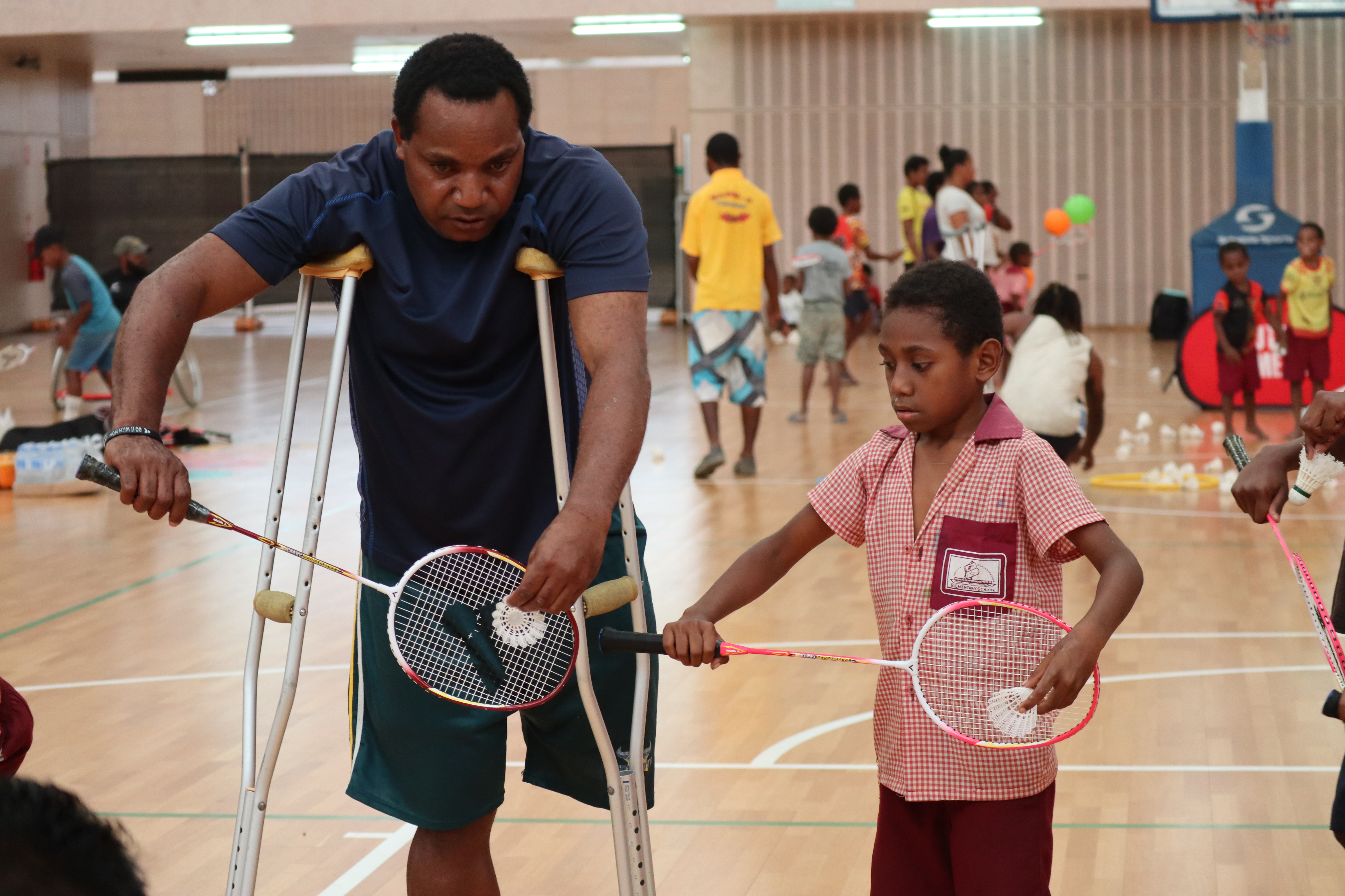 Para athlete teaches young boy how to play badminton Papua New Guinea