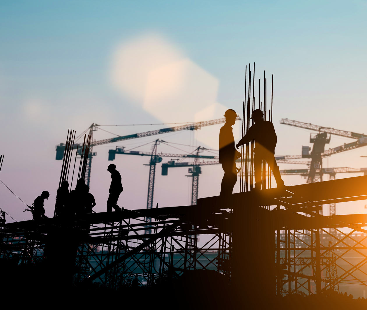 Construction workers conversing whilst standing on a steel structure