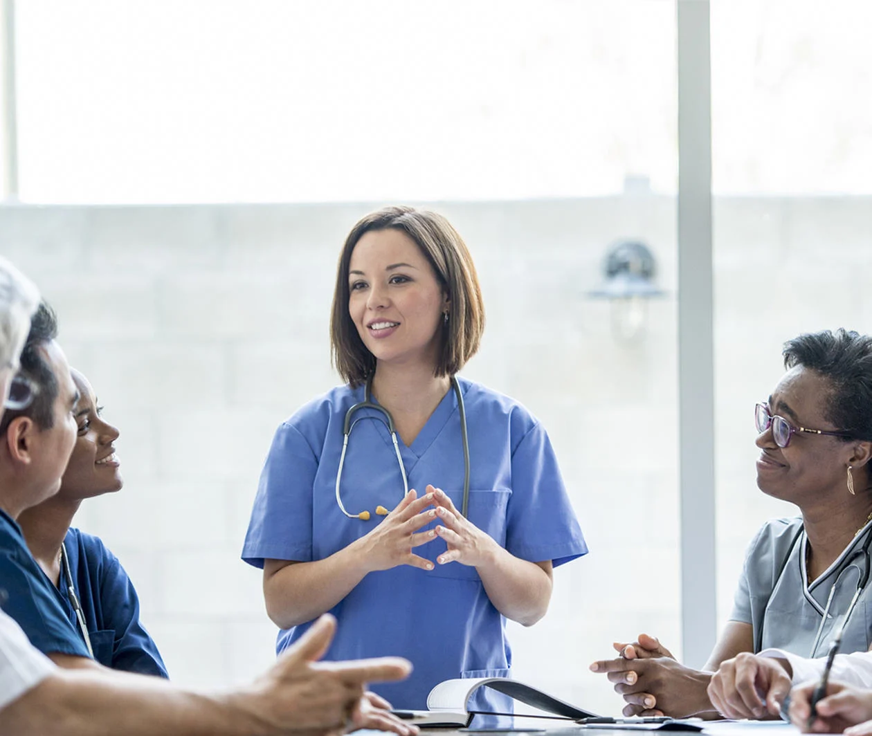 Female healthcare expert educating a table of other healthcare professionals 