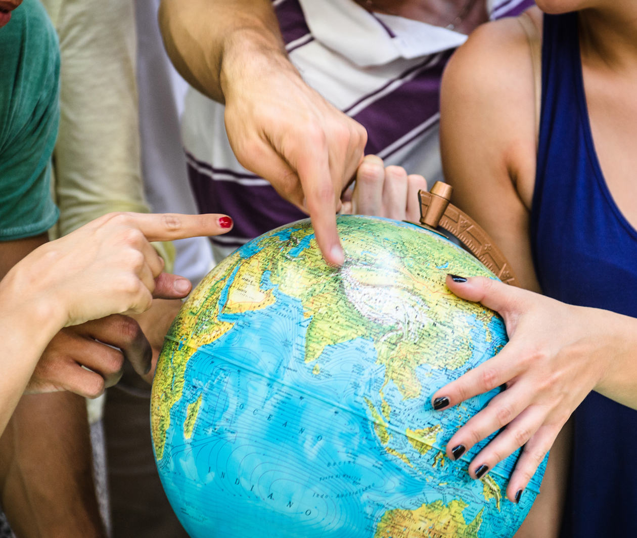 Image of hands pointing to different places on a globe