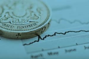 A coin sits on top of a line graph on a piece of paper – a metaphor for managing finances.