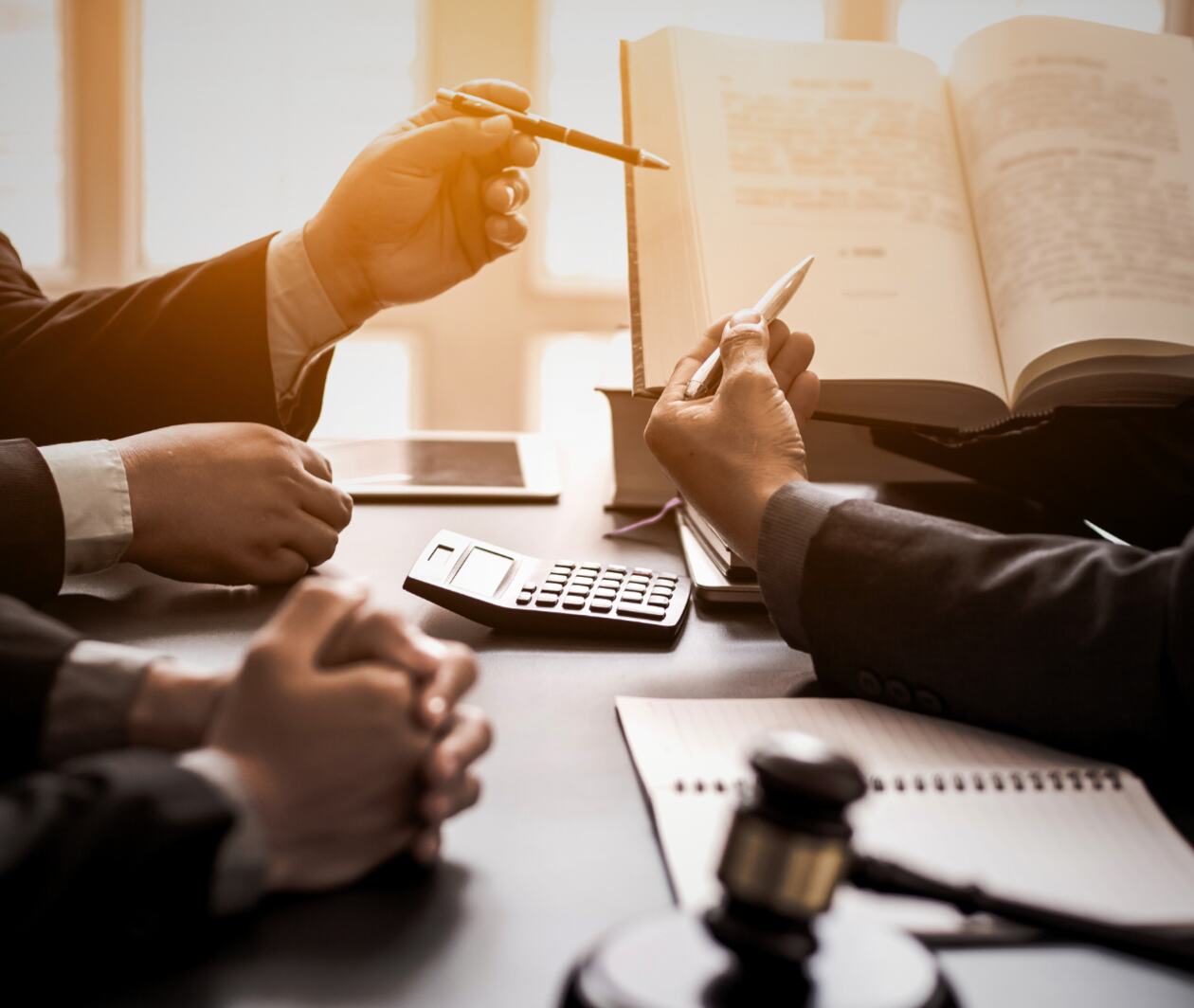 A group of people sitting at a table with a book and a gavel