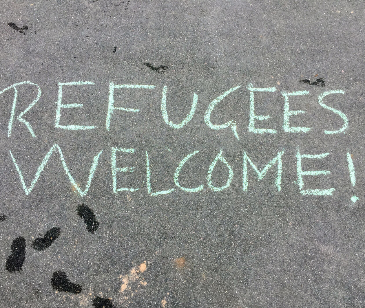 Chalk writing on the floor saying "Refugees Welcome!"