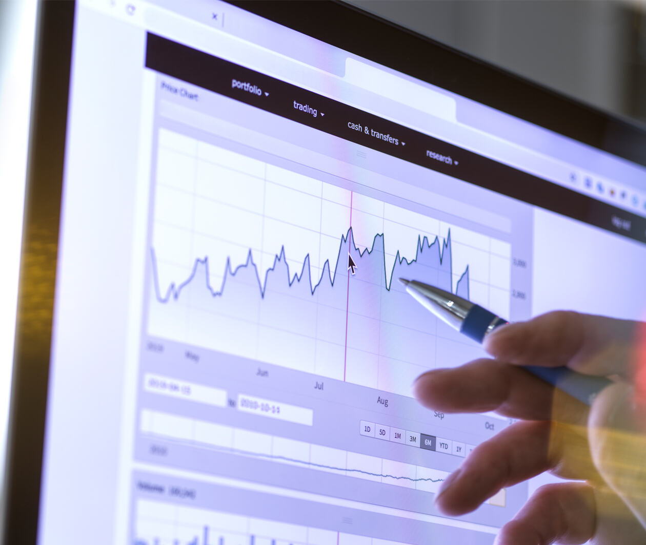 Closeup of a stock broker's hand analyzing the performance of a company stock on the internet on a price chart.