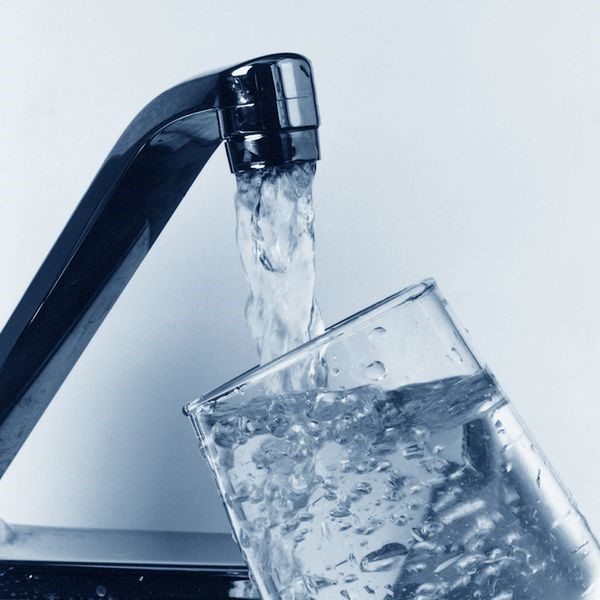 A tap filling a glass with water.