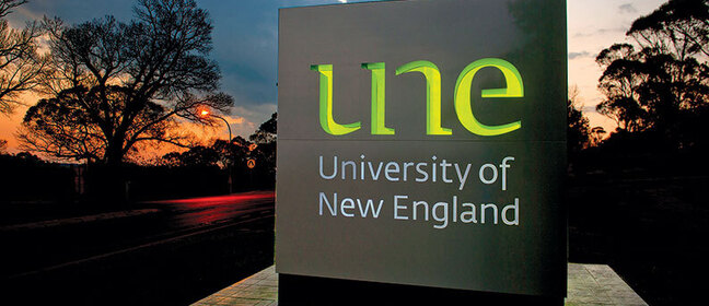 University of New England sign against a sunset background